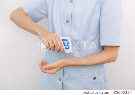 Temperature measurement gun in doctor hands. Close-up shot of doctor wearing protective surgical mask ready to use infrared isometric thermometer gun to check body temperature for virus symptoms. 85690334