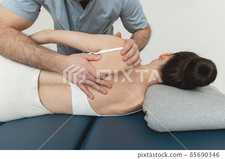 Back massage. Chiropractor or osteopath fixing back during visit in manual therapy clinic. Doctor doing shoulder blade therapy. Scoliosis. Posture Correction. Chiropractic treatment, Back pain relief. Back massage. Chiropractor or osteopath fixing back during visit in manual therapy clinic. Doctor doing shoulder blade therapy. Scoliosis. Posture Correction. Chiropractic treatment, Back pain relief. 85690346