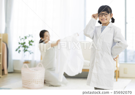 A girl in a lab coat and a housewife folding laundry 85692070