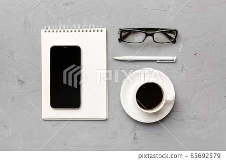 Modern office desk table with notebook, smartphone and other supplies with cup of coffee. Blank notebook page for you design. Top view, flat lay Modern office desk table with notebook, smartphone and other supplies with cup of coffee. Blank notebook page for you design. Top view, flat lay 85692579