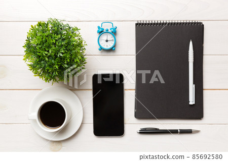 Modern office desk table with notebook, smartphone and other supplies with cup of coffee. Blank notebook page for you design. Top view, flat lay Modern office desk table with notebook, smartphone and other supplies with cup of coffee. Blank notebook page for you design. Top view, flat lay 85692580