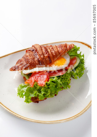 Sandwich from croissant with salted salmon, cucumber, fried egg and lettuce 85697005