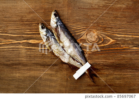 Two salted air-dried sabrefish with paper labels on tails on wooden background 85697067
