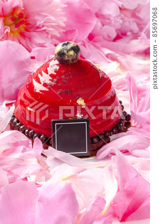 Dessert with cherry mousse on chocolate sponge cake covered with berry confit among pink peony petals 85697068