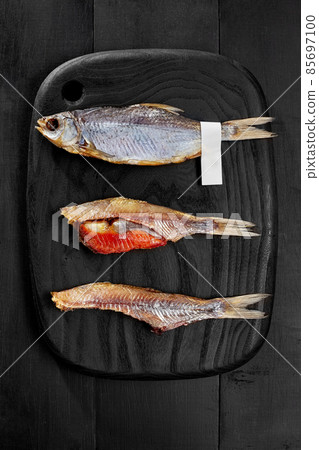 Whole and skinned salted air-dried roach fish with caviar on black wooden board Whole and skinned salted air-dried roach fish with caviar on black wooden board 85697100