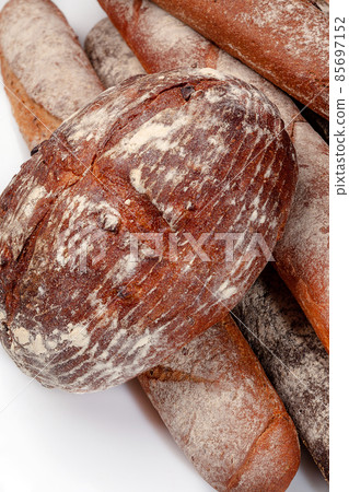 Freshly baked round wheat bread and whole grain baguettes isolated on white 85697152