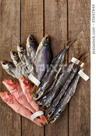Dried salted roach, sabrefish and red mullets with labels on tails on wooden background 85697649