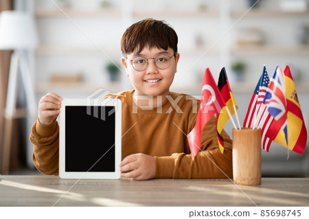 Positive chubby asian boy showing digital tablet with blank screen Positive chubby asian boy showing digital tablet with blank screen 85698745