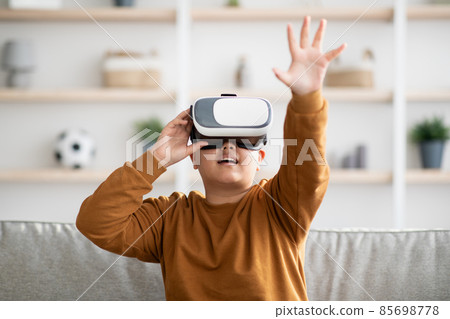Excited kid using VR glasses, touching something invisible Excited kid using VR glasses, touching something invisible 85698778