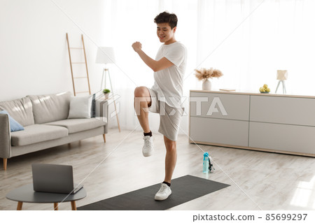 Asian guy doing high knee to elbow exercise using laptop 85699297