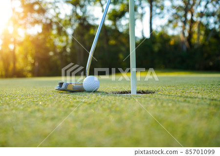 Golf clubs and golf balls on a green lawn in a beautiful golf course with morning sunshine. golf ball on green grass ready to hit on golf course background 85701099