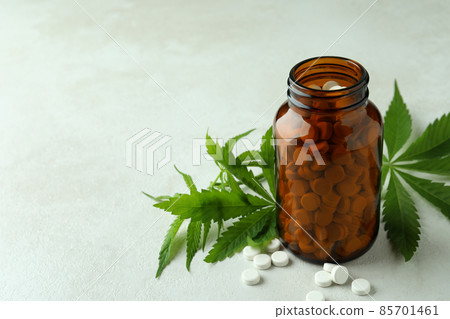 Bottle with pills and cannabis leaves on white textured background Bottle with pills and cannabis leaves on white textured background 85701461