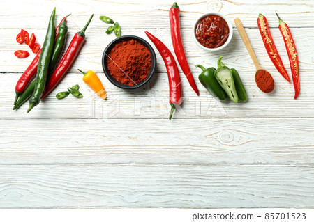 Hot peppers, sauce and powder on white wooden background Hot peppers, sauce and powder on white wooden background 85701523