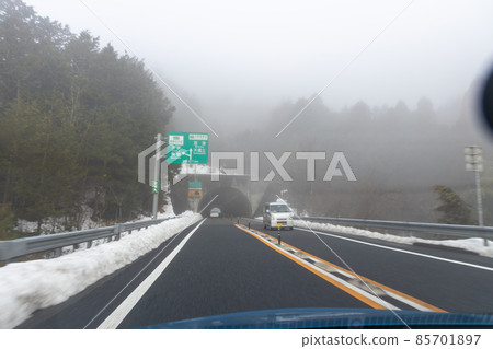 在霧濛濛的京都十函高速公路上行駛的汽車乘客座位上的風景，路邊有雪 85701897