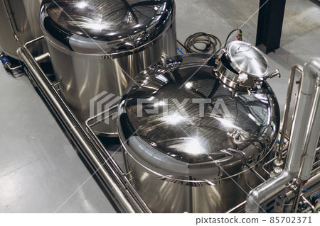 Modern Beer Factory. Steel tanks for beer fermentation and storage. Brewery. Modern beer plant with brewering kettles Modern Beer Factory. Steel tanks for beer fermentation and storage. Brewery. Modern beer plant with brewering kettles 85702371