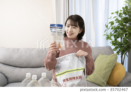 A woman who smiles and checks the contents of the emergency carry-out bag 85702467