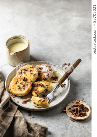 Syrniki or cottage cheese fritters with chocolate poured with condensed milk in the process of eating on ceramics plate with text space Syrniki or cottage cheese fritters with chocolate poured with condensed milk in the process of eating on ceramics plate with text space 85705021