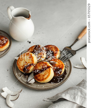 Syrniki or cottage cheese fritters with with chocolate sauce and coconut on ceramics plate Syrniki or cottage cheese fritters with with chocolate sauce and coconut on ceramics plate 85705029