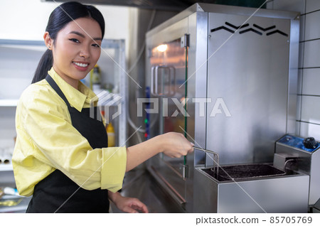 Asian young girl working in the kitchen and preparing food Asian young girl working in the kitchen and preparing food 85705769