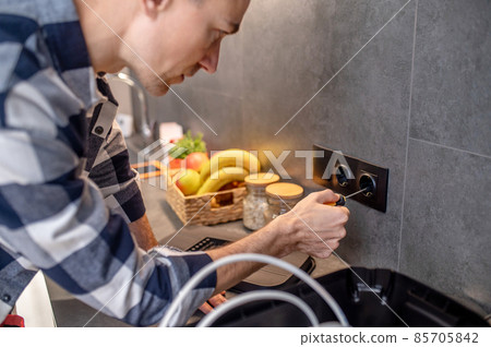 Close-up photo of man touching socket with screwdriver 85705842