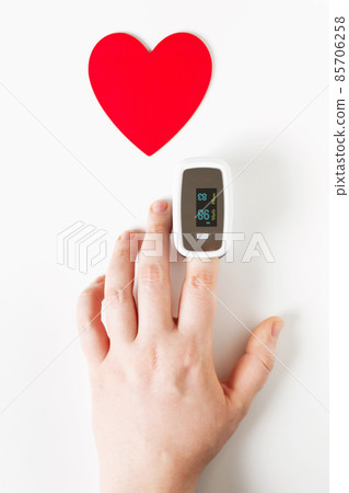 Covid Valentine day concept, hand with pulse oximeter on a finger and a heart symbol 85706258