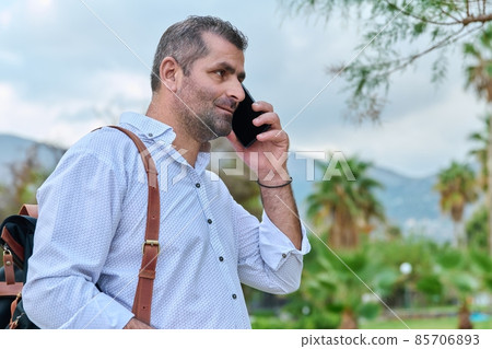 Mature man talking on the phone outdoors. Mature man talking on the phone outdoors. 85706893