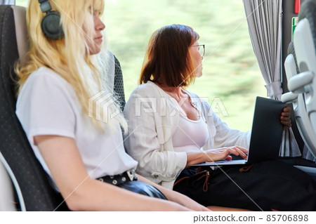 Middle-aged woman in a bus using a laptop. Middle-aged woman in a bus using a laptop. 85706898