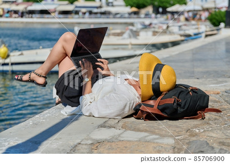 Woman in hat typing on laptop, water bay boat background Woman in hat typing on laptop, water bay boat background 85706900