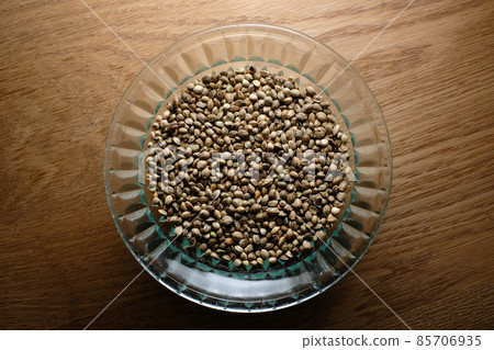 Hemp seeds, marijuana grain in a round glass plate on wooden textured background Hemp seeds, marijuana grain in a round glass plate on wooden textured background 85706935