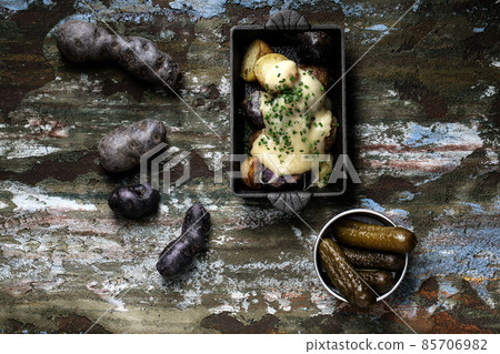 Marinated pickled cucumbers with cooked and raw blue potatoes on forest green clay background 85706982