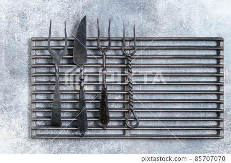 Vintage forks and knife on the grill grate above Vintage forks and knife on the grill grate above 85707070