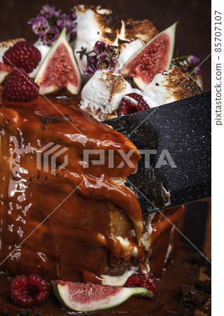 Caramel cake with wild berries, cream and figs on brown background Caramel cake with wild berries, cream and figs on brown background 85707107