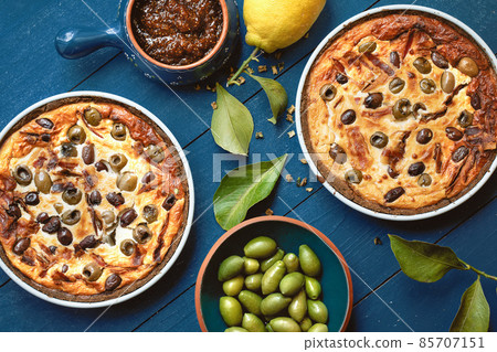 Homemade tart with olives on old blue wooden background decorated with fresh lemon, fresh olives, lemon leafs and fig jam from above Homemade tart with olives on old blue wooden background decorated with fresh lemon, fresh olives, lemon leafs and fig jam from above 85707151