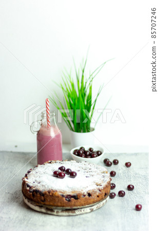 Homemade cherry pie and red cherry smoothie and sprinkled with berries on a gray table, close-up. Summer breakfast 85707246