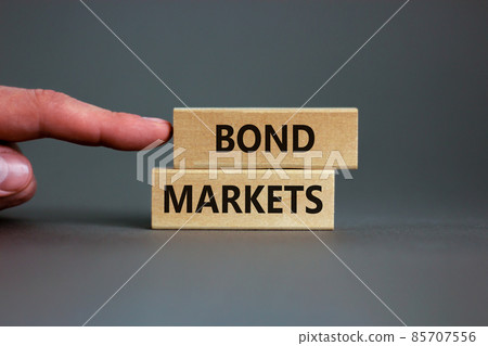Bond markets symbol. Wooden blocks with words 'Bond markets' on beautiful grey background, copy space. Businessman hand. Business and bond markets concept. Bond markets symbol. Wooden blocks with words 'Bond markets' on beautiful grey background, copy space. Businessman hand. Business and bond markets concept. 85707556