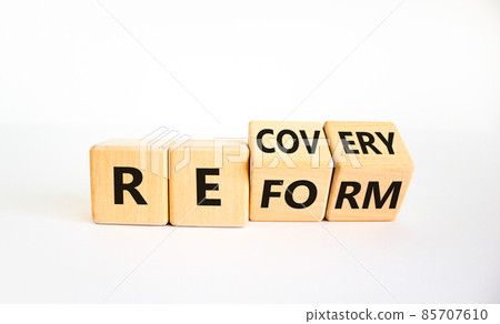 Recovery and reform symbol. Turned cubes and changed the word 'recovery' to 'reform'. Beautiful white background. Business and recovery - reform concept. Copy space. Recovery and reform symbol. Turned cubes and changed the word 'recovery' to 'reform'. Beautiful white background. Business and recovery - reform concept. Copy space. 85707610
