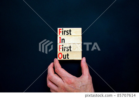FIFO first in first out symbol. Concept words FIFO first in first out on wooden blocks. Beautiful black table, black background. Businessman hand. Business FIFO first in and out concept. Copy space. FIFO first in first out symbol. Concept words FIFO first in first out on wooden blocks. Beautiful black table, black background. Businessman hand. Business FIFO first in and out concept. Copy space. 85707614