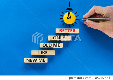 Better new me symbol. Wooden blocks with words 'new me like old me only better'. Light bulb icon. Businessman hand, pen. Beautiful blue background, copy space. Business and better new me concept. 85707651