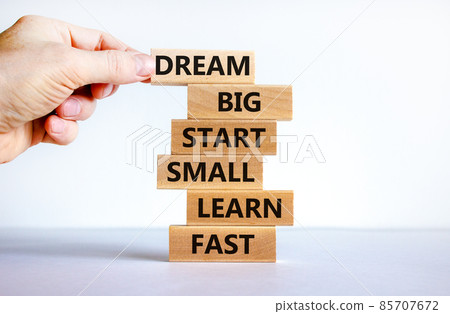 Dream big start small symbol. Words 'dream big start small learn fast' on wooden blocks on a beautiful white background. Businessman hand. Business, motivational and dream big start small concept. Dream big start small symbol. Words 'dream big start small learn fast' on wooden blocks on a beautiful white background. Businessman hand. Business, motivational and dream big start small concept. 85707672
