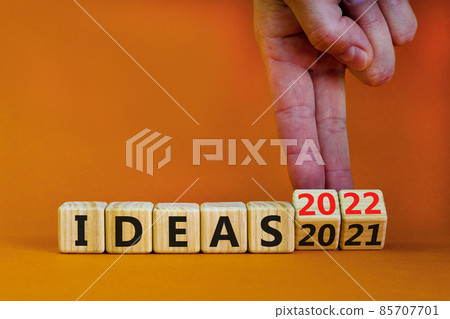 2022 ideas new year symbol. Businessman turns wooden cubes and changes words 'Ideas 2021' to 'Ideas 2022'. Beautiful orange background, copy space. Business, 2022 ideas new year concept. 85707701