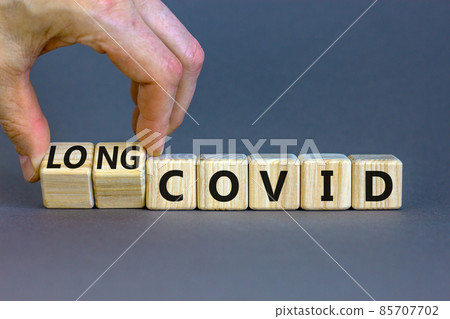 Long covid symbol. Doctor turnes wooden cubes and changes words 'covid' to 'long covid'. Beautiful grey table, grey background, copy space. Medical, covid-19 pandemic long covid concept. Long covid symbol. Doctor turnes wooden cubes and changes words 'covid' to 'long covid'. Beautiful grey table, grey background, copy space. Medical, covid-19 pandemic long covid concept. 85707702
