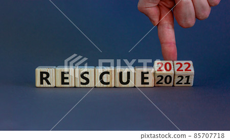 2022 rescue new year symbol. Businessman turns wooden cubes and changes words 'rescue 2021' to 'rescue 2022'. Beautiful grey background, copy space. Business, 2022 rescue new year concept. 85707718