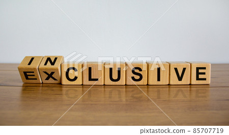 Symbol for a better inclusive. Inverted cube and changed word exclusive to inclusive. Beautiful wooden table, white background. Copy space. 85707719