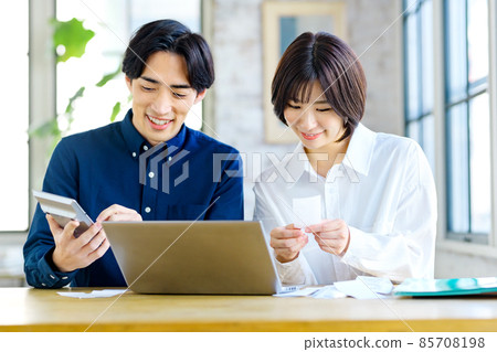 一對年輕夫婦在家查看收據時計算的最終納稅申報表的圖像 一對年輕夫婦在家查看收據時計算的最終納稅申報表的圖像 85708198