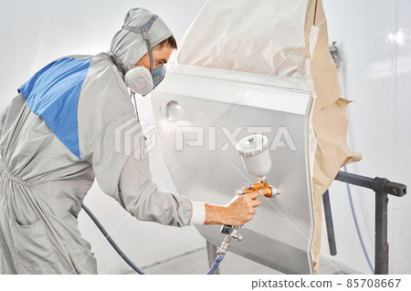 Painting the rear door of the car. Car painter in special painting chamber, wearing costume and protective gear. Car service station. Restoring a car after an accident 85708667