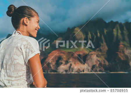 Hawaii cruise Asian tourist woman enjoying sightseeing looking at Na Pali Coast beach mountain landscape. Kauai island travel popular landmark, USA 85708935