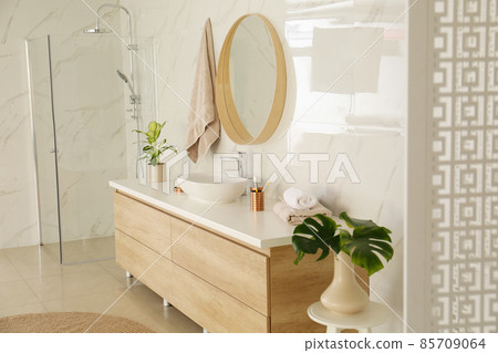 Round mirror over vessel sink in stylish bathroom interior 85709064