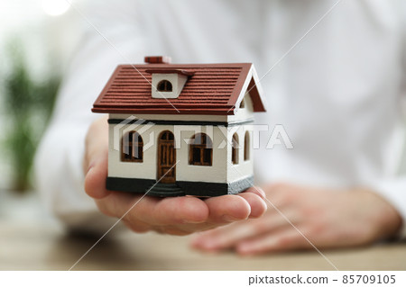 Real estate agent holding house model indoors, closeup Real estate agent holding house model indoors, closeup 85709105