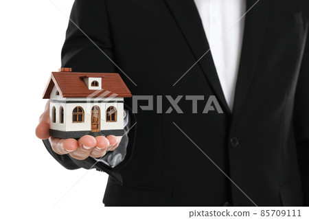 Real estate agent holding house model on white background, closeup Real estate agent holding house model on white background, closeup 85709111