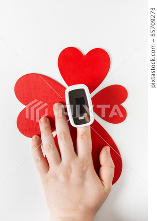 Covid Valentine day concept, hand with pulse oximeter on a finger and a heart symbol 85709273
